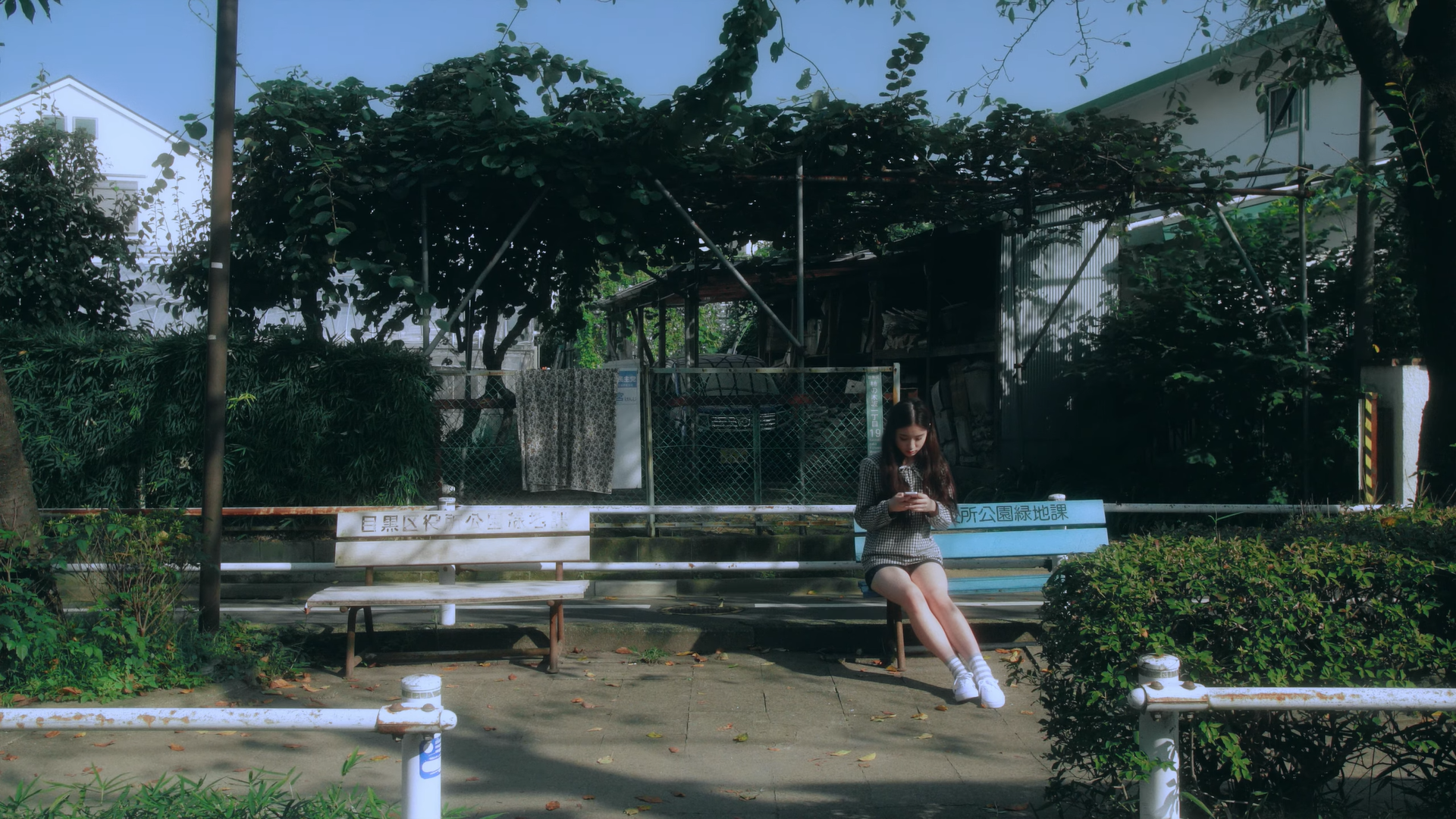 Heejin sitting on a bench, looking at her phone.